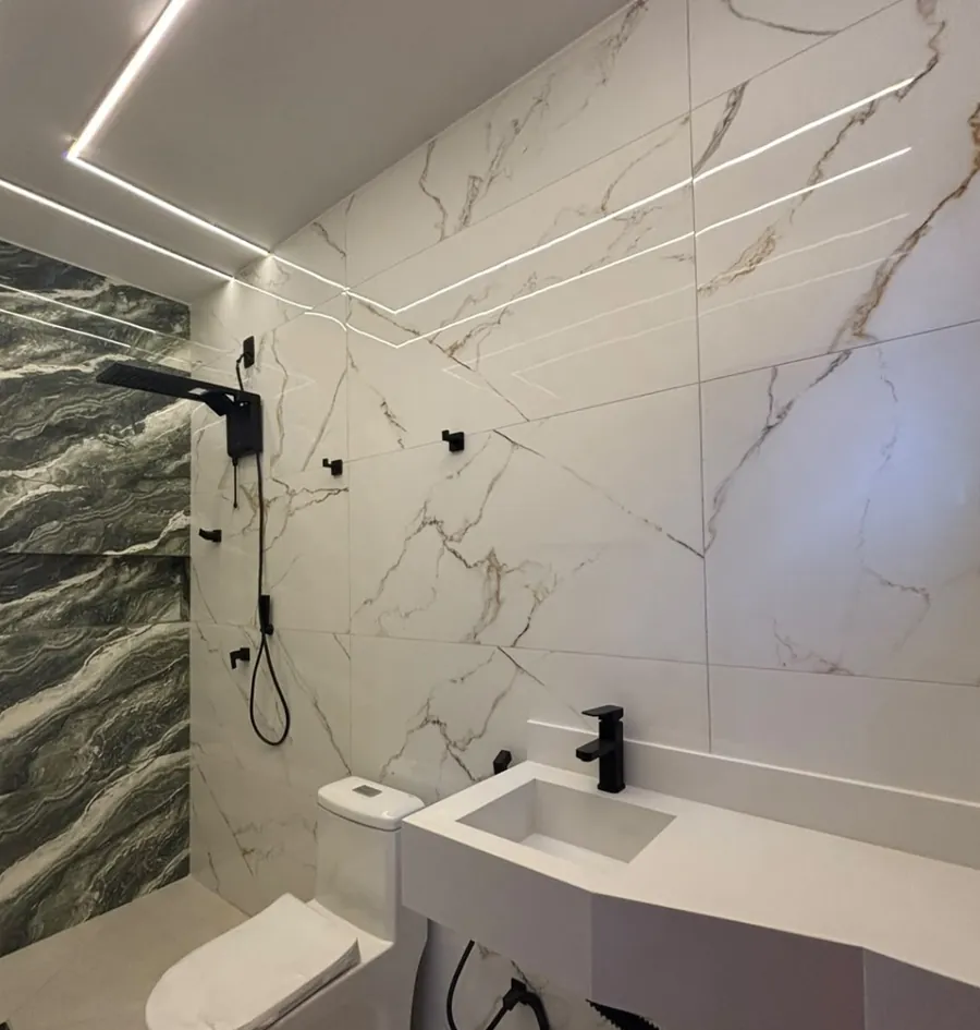 Banheiro com revestimento tipo mármore, iluminação em LED e metais pretos