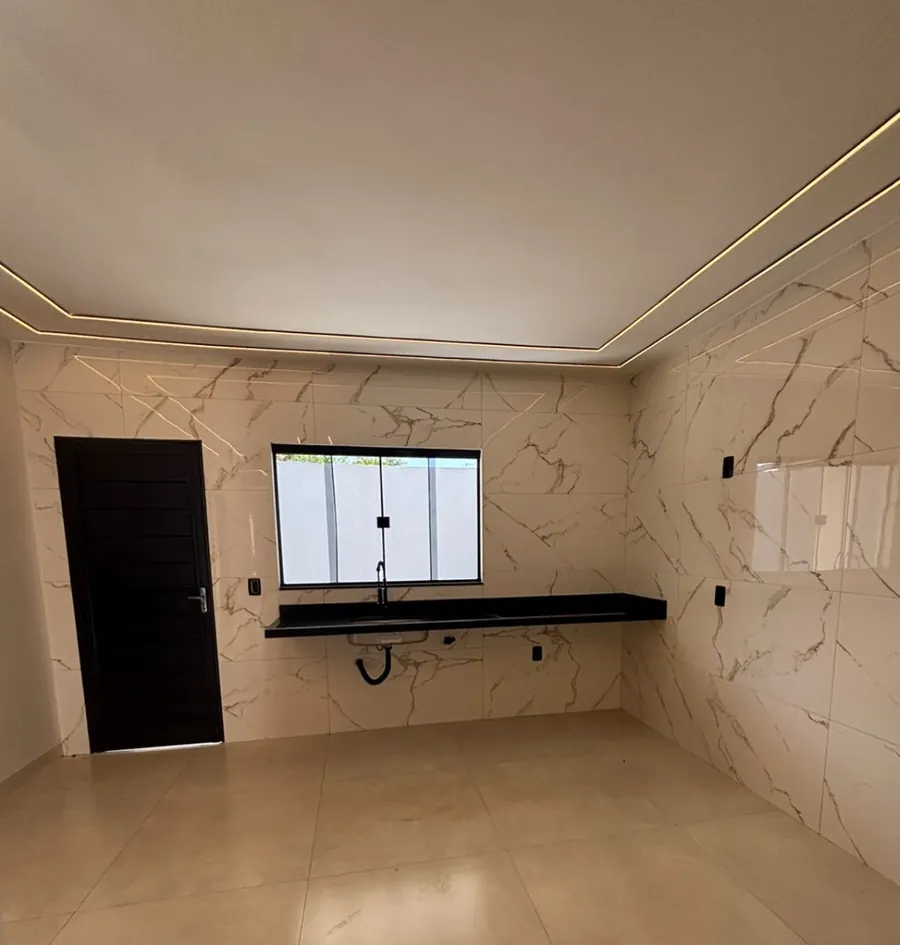 Cozinha com revestimento tipo mármore, bancada escura e janela