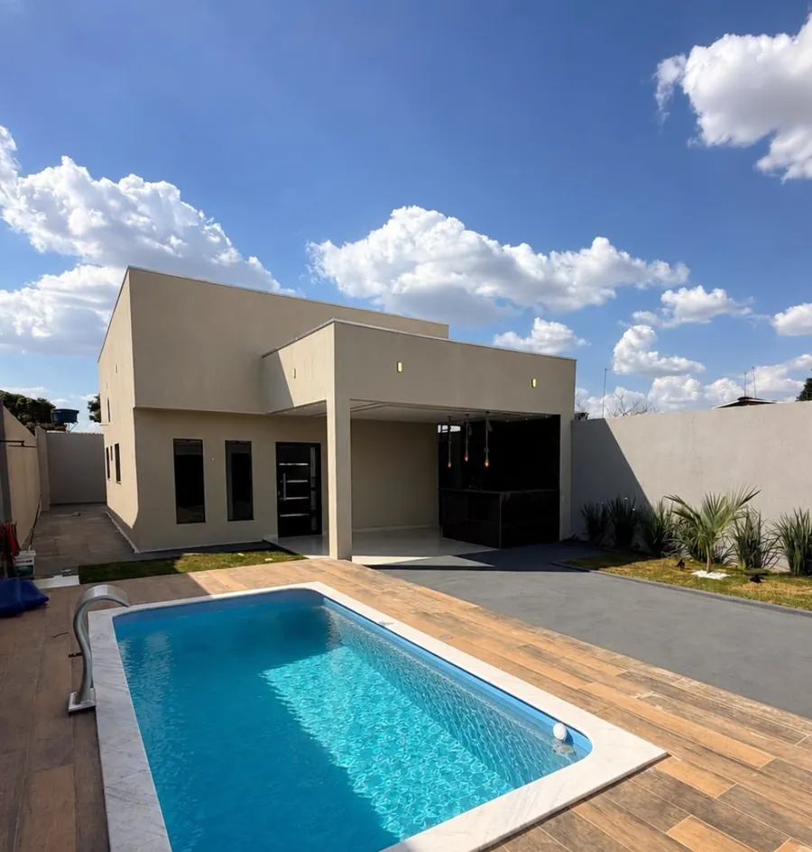 Piscina em frente à casa, com deck de madeira e céu azul