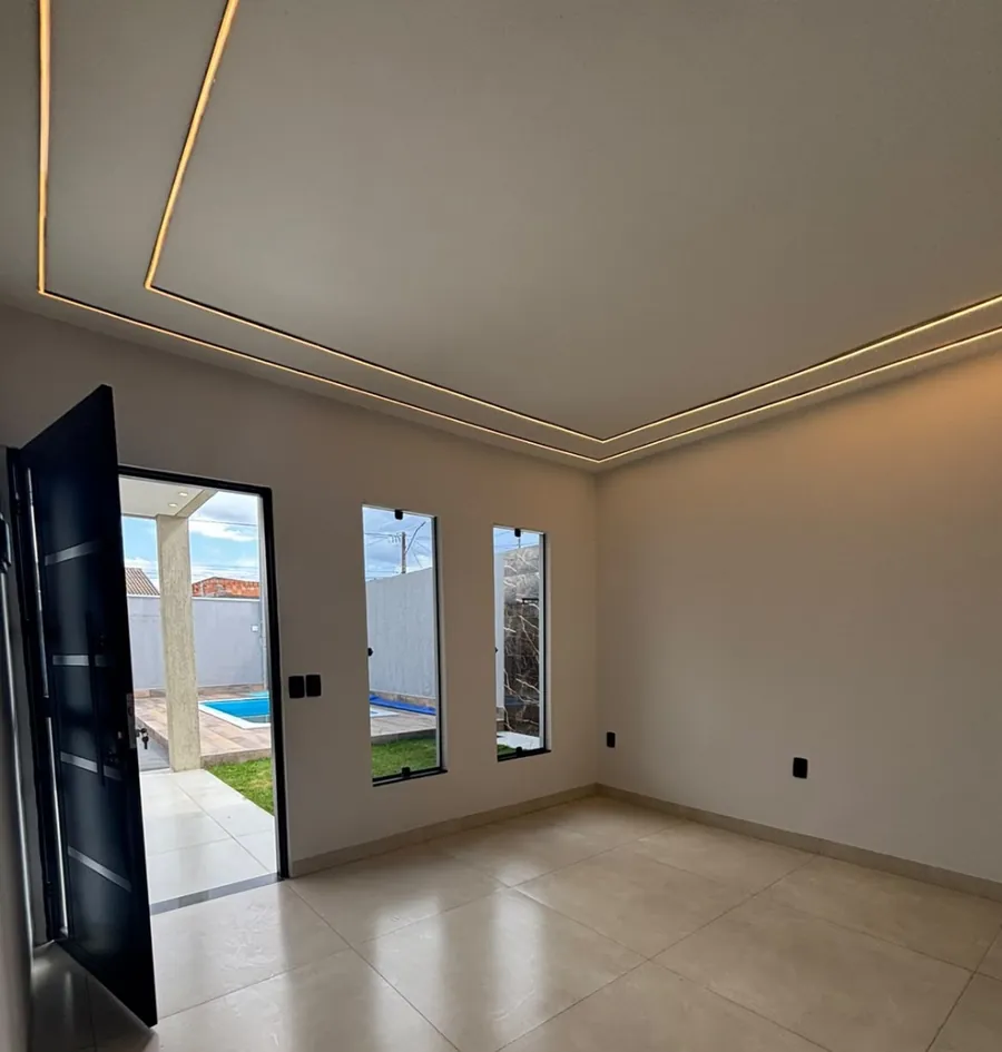 Sala com iluminação em perfil de LED no teto e porta aberta para o quintal