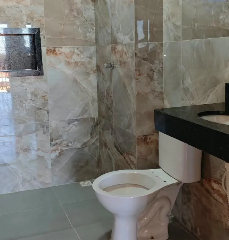 Banheiro com revestimento tipo mármore e bancada escura