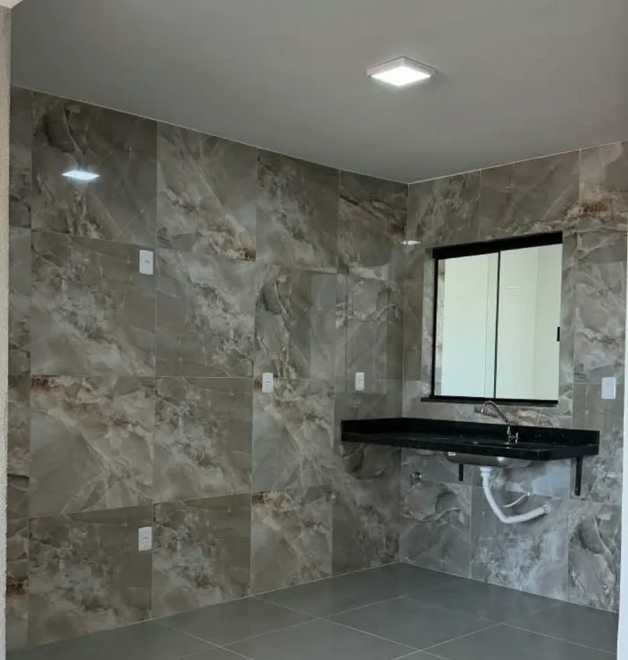 Cozinha com revestimento em porcelanato e bancada escura com pia sob a janela