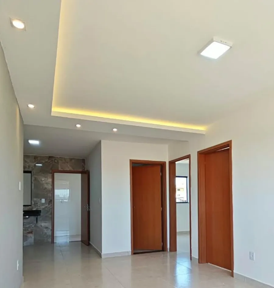 Sala com forro de gesso rebaixado e iluminação em LED, e as portas dos cômodos ao fundo